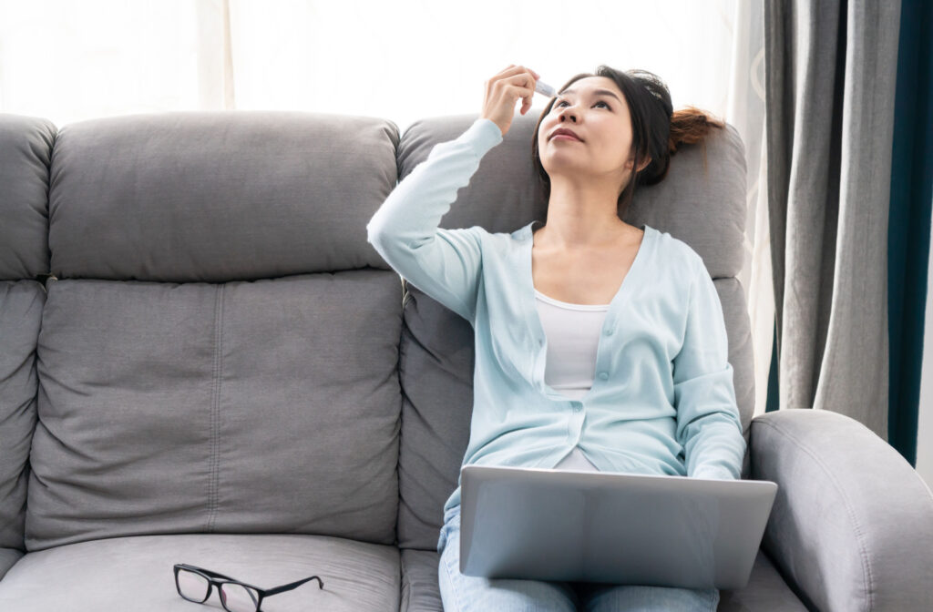 A woman applying artificial tears on her right eye to prevent eye strain.
