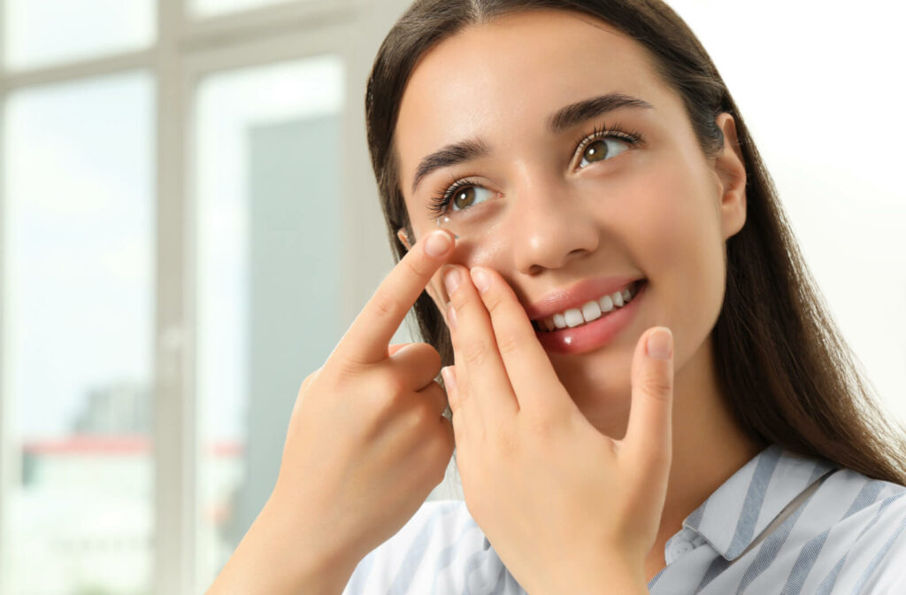 A woman putting soft contact lenses in her eye at home.